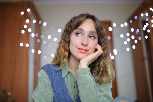 A beautiful young girl smiles and holds her hands to her face