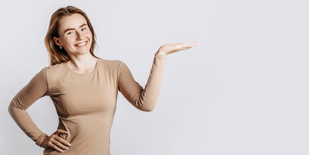 Beautiful young girl smiling and pointing her hand to the side at on a white isolated background