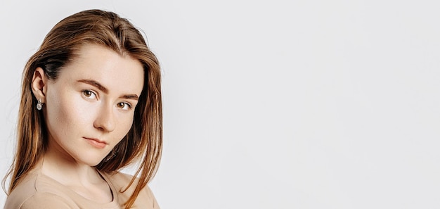 Beautiful young girl smiling and posing looking at the camera on a white isolated background Positive brunette woman in a beige jumper Kind look