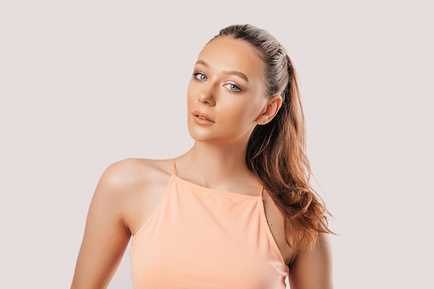 Beautiful young girl smiling and posing looking at the camera on a white isolated background. Positive brunette woman. Kind look. Beauty face.