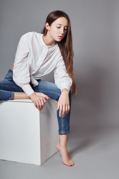 Beautiful young girl smiling sitting on a cube