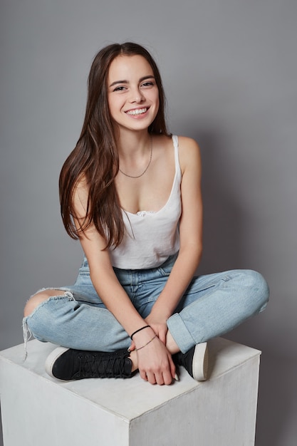 Beautiful young girl smiling sitting on a cube