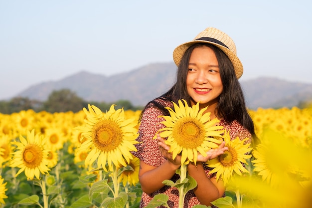 Beautiful young girl at sunflower field with blue sky