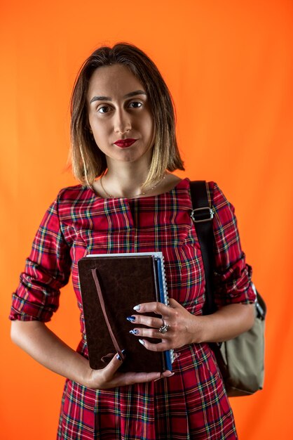 Beautiful young girl teacher standing with books in hands isolated on plain background