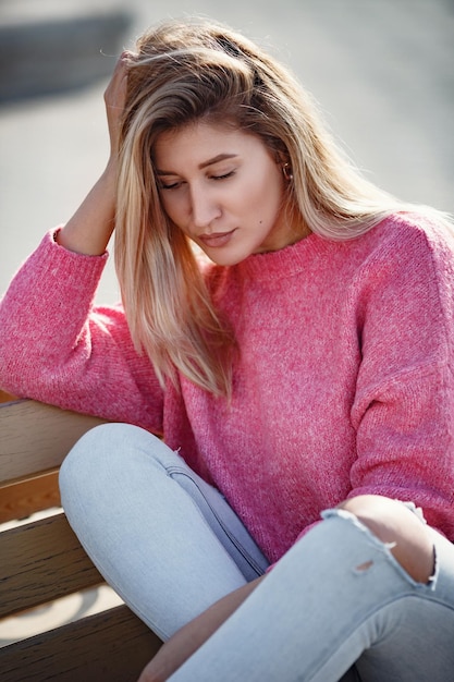 Beautiful young girl on a walk in the autumn city Beautiful woman in a sweater Fashion portrait stylish pretty woman outdoor Young woman having fun in city Street fashion