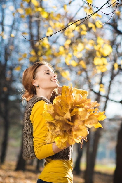 Beautiful young girl walks in the autumn park with fallen yellow leaves