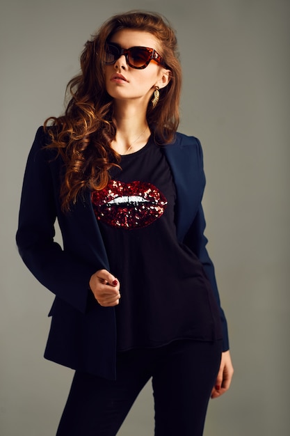 Beautiful young girl wearing a jacket, shirt and pants posing on a gray background. studio photo. the concept of fashion. horizontal photo