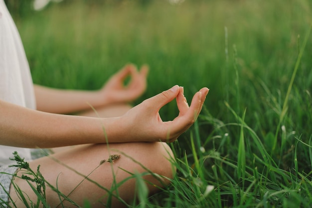 Beautiful young girl in a white T shirt doing yoga in a beautiful field. Healthy lifestyle