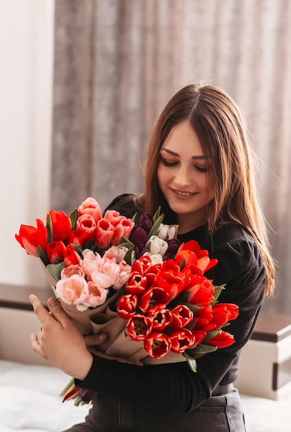 Beautiful young girl with a big bouquet of tulip color