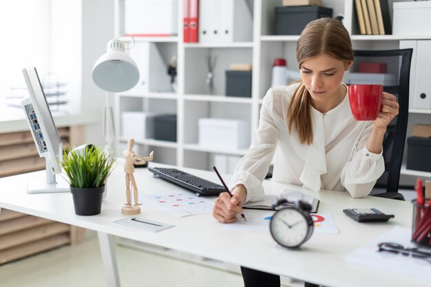 Beautiful young girl with blond hair. A girl in a white blouse is working in the office. 