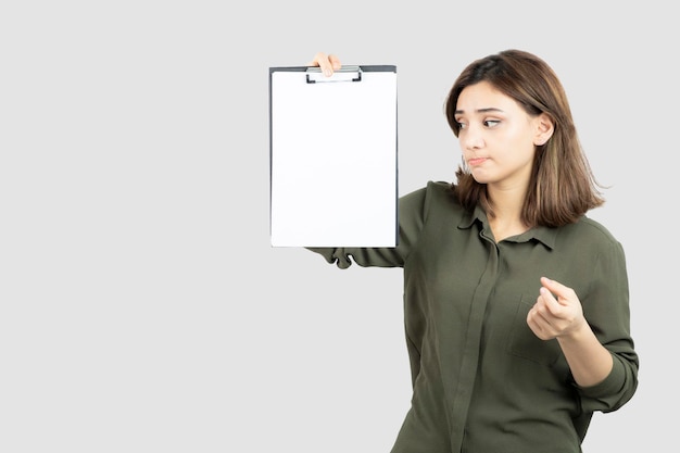 Beautiful young girl with clipboard standing and posing over white. High quality photo