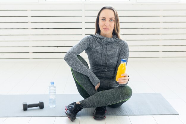 Beautiful young girl with a fitness smoothie, water bottle and dumbbell