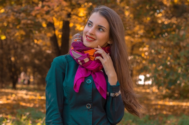 Beautiful young girl with a pink handkerchief around your neck stands in the Park and smiles