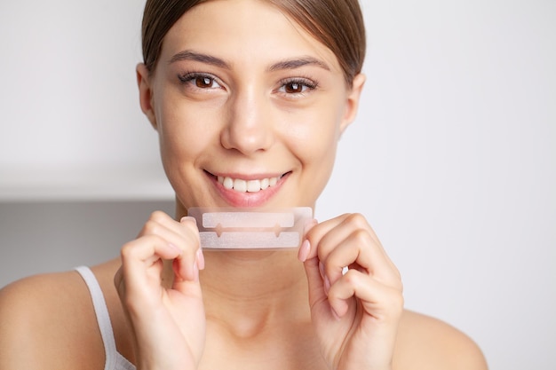 Beautiful Young Girl With White Teeth Holding in Hands Stripes For Teeth Whitening