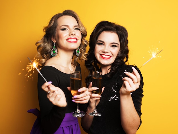 Beautiful young girls ready for a party laughing and holding sparklers