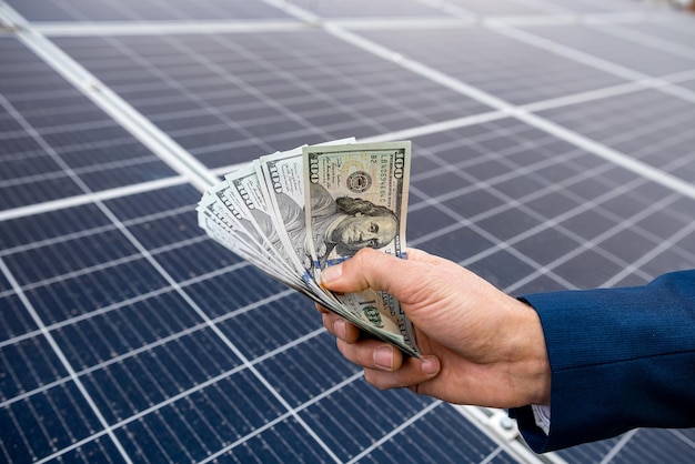 Beautiful young gorgeous worker hands holding round sum of money for installing solar panels