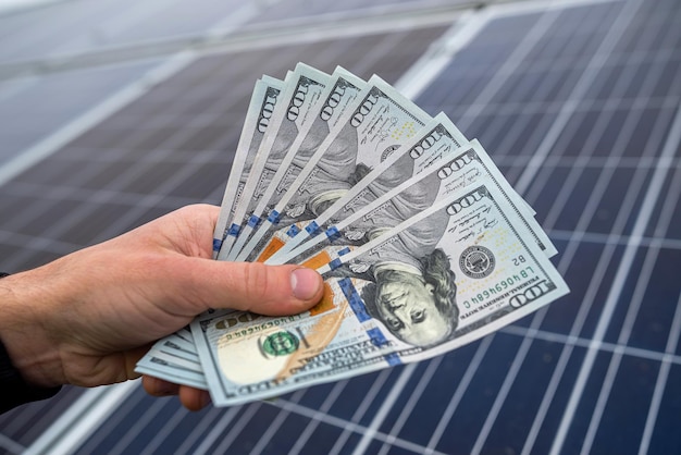 Beautiful young gorgeous worker hands holding round sum of money for installing solar panels