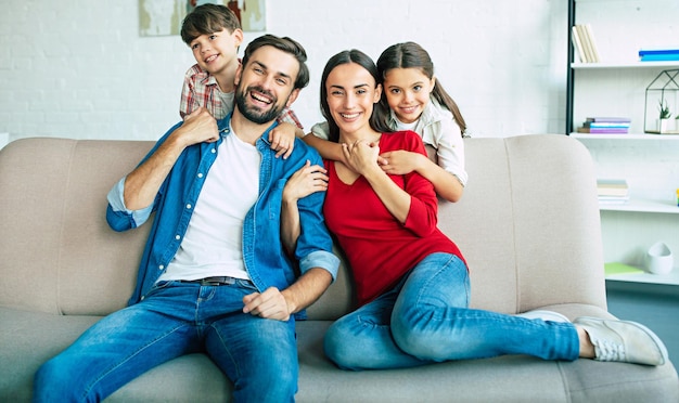 Beautiful young happy family relaxing together at home smiling and hugging