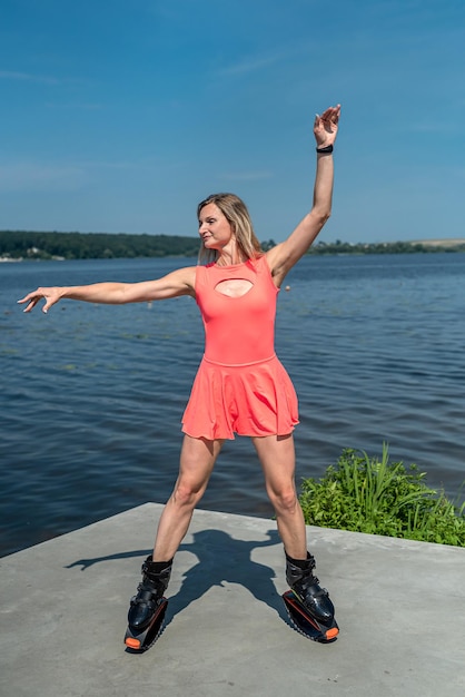 Beautiful young healthy girl with good physical condition trains on springs near a simple lake