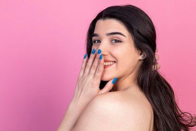 Beautiful young lady holding her hand to her face and smiling for the camera