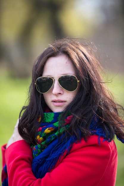 Beautiful young lady in red coat and black sunglasses