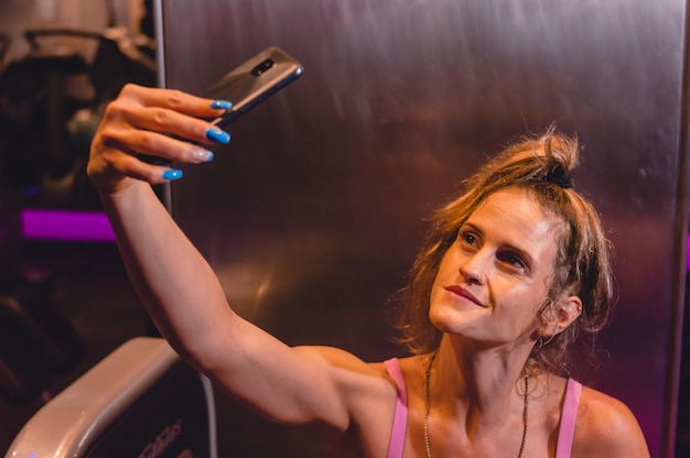 beautiful young latin caucasian woman in the gym takes a selfie