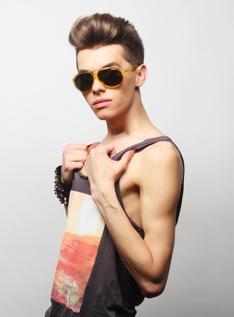 The beautiful young man in sunglasses on a white background