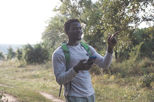 The beautiful young man with a backpack is hiking in the forest