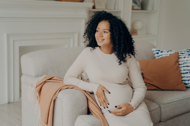 Beautiful young mixed race pregnant woman hugging her tummy