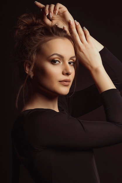 Beautiful young model with perfect makeup posing at studio over the dark background