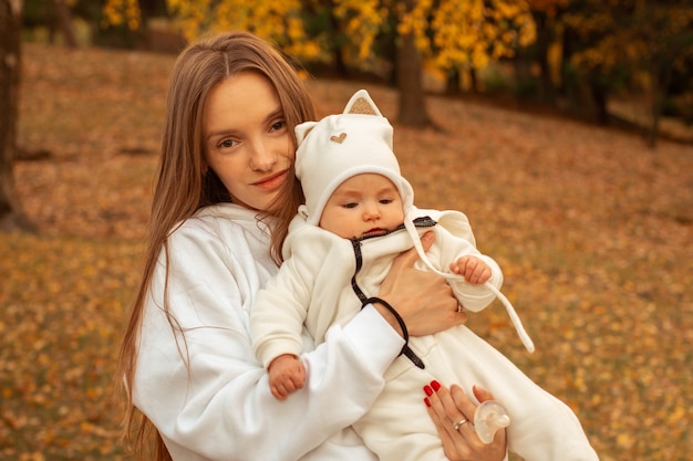 Beautiful young mom with baby girl in autumn