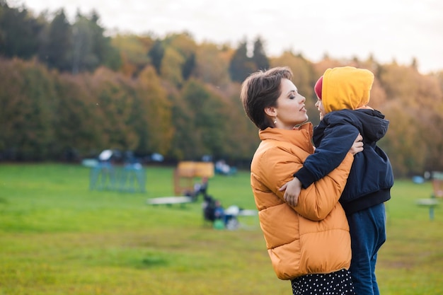 A beautiful young mother holds her little son in her arms mother and son spend time together on the