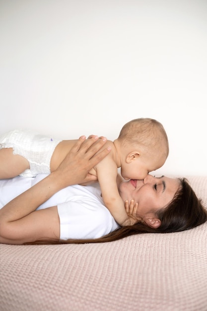 A beautiful young mother plays and cuddles with her baby in her bedroom on the bed Love motherhood Weasel tenderness Lifestyle