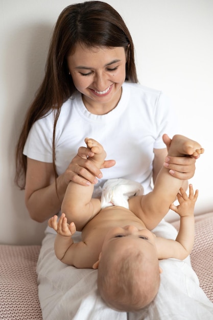 A beautiful young mother plays and cuddles with her baby in her bedroom on the bed Love motherhood Weasel tenderness Lifestyle