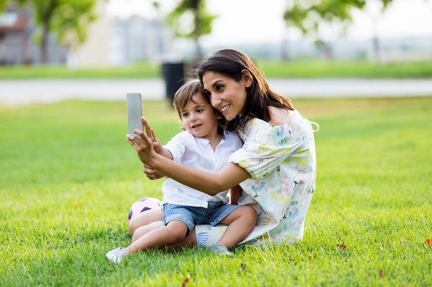 Beautiful young mother with her son taking a selfie in the park.