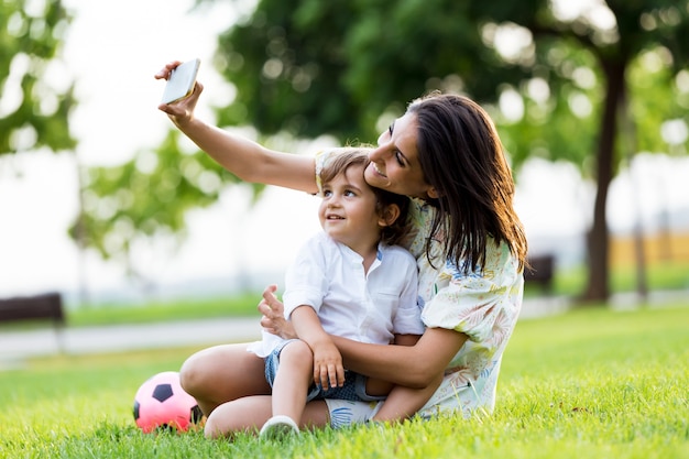 Beautiful young mother with her son taking a selfie in the park.