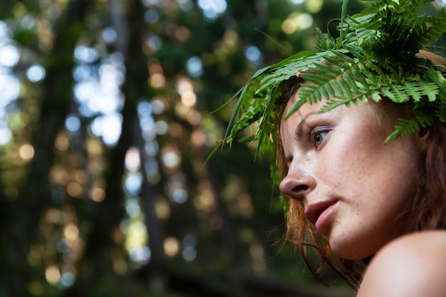 Photo a beautiful young nude woman with fern wreath on her head enjoying nature in the forest river