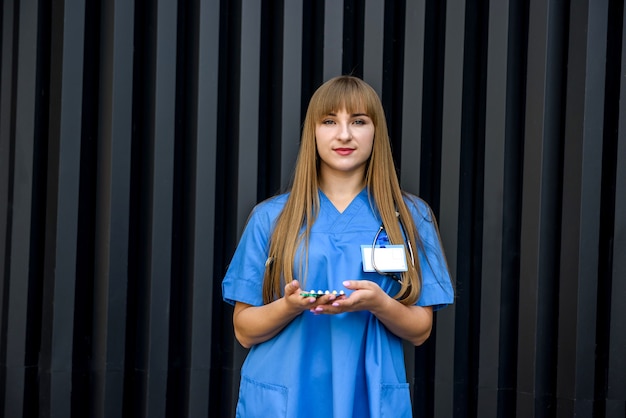 Beautiful young nurse in blue uniform holds pills