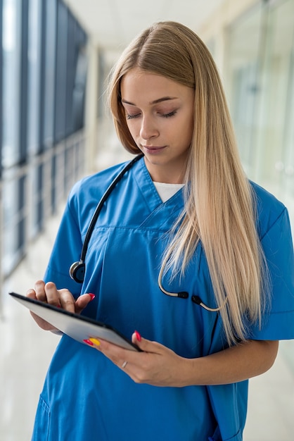 Beautiful young nurse standing in the hallway with a tablet