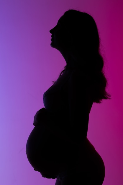 Beautiful young pregnant woman in lingerie in beautiful neon ightl