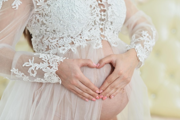 Beautiful young pregnant woman making heart sign