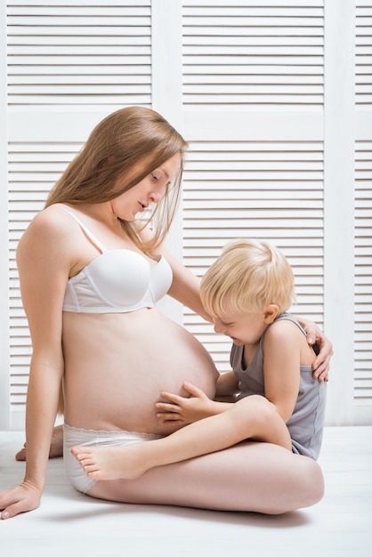 Beautiful young pregnant woman sitting on floor with her eldest son.