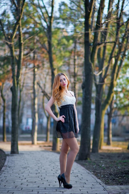 Beautiful young red-haired girl in a dress in the park.Beautiful young girl with red long curly hair