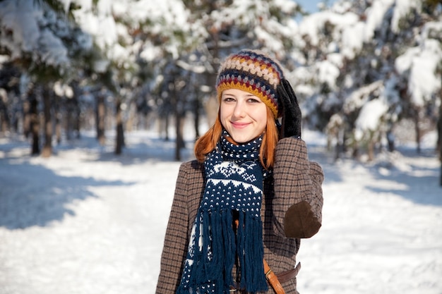 Beautiful young red-haired woman in winter park