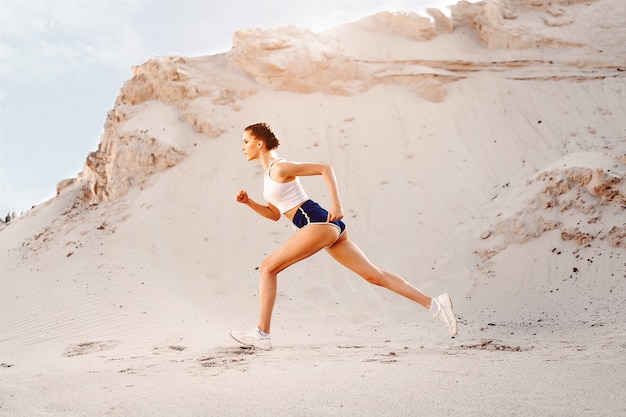 Beautiful young sexy athletic girl running on the nature summer morning. Woman do work out near the lake. Healthy lifestyle. Fitness training outdoor.