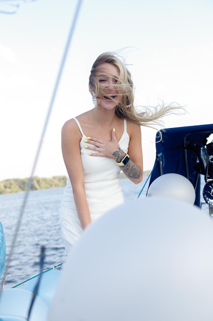 Beautiful young sexy blond woman in a dress and makeup summer trip on a yacht with white sails on the sea or ocean in the Gulf marine of the wind and the breeze in the sun tans romantic