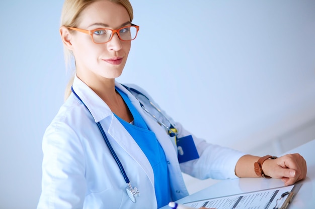 Beautiful young smiling female doctor sitting at the desk