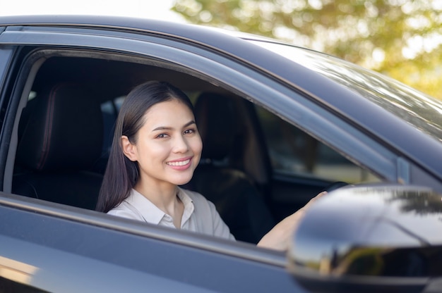 A beautiful young smiling woman driving her car, insurance and finance concept