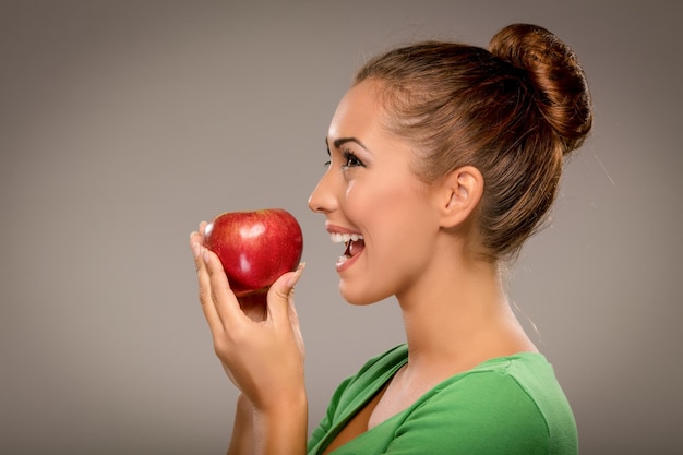 Beautiful young smiling woman holding red apple.