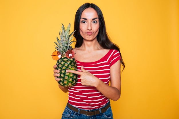 Beautiful young smiling woman with pineapple in hands on orange background Tropical fruits Healthy eating